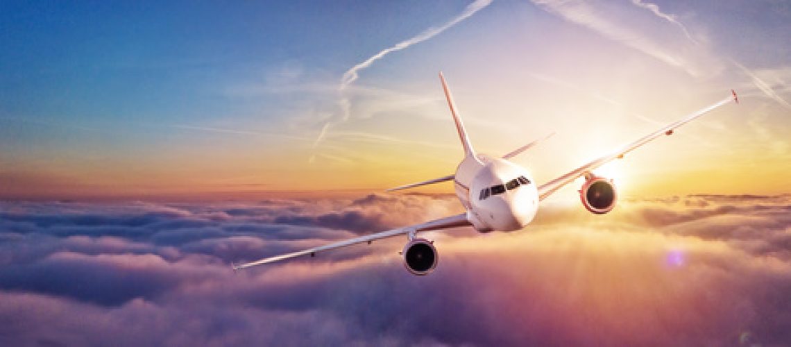 Commercial airplane flying above clouds in dramatic sunset light. High resolution of image. Fast Travel and transportation concept